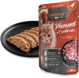 Leonardo cat food package with pheasant and cranberries flavor, next to a black plate with cat treats.